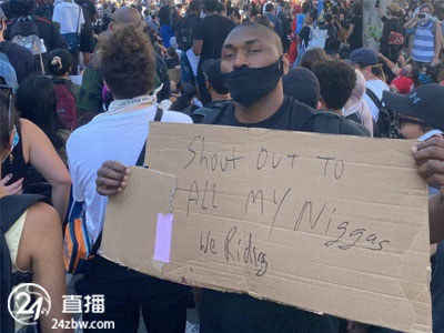 阿泰斯特用纸板写着“致敬黑人兄弟”，在街上参加了抗议